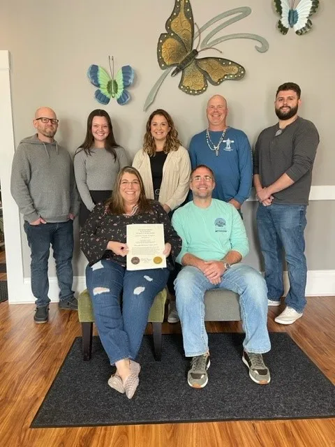Chrysalis Recovery Center team receiving the Recovery Friendly Workplace designation in front of butterfly wall art at the Concord, NH office